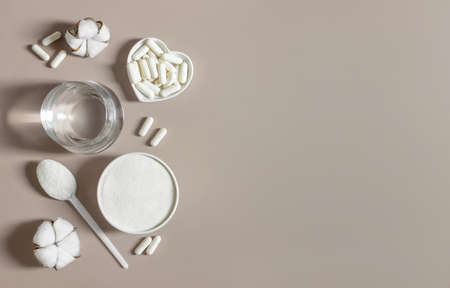 Collagen powder and pills on a beige background. A natural supplement for bone and joint health, skin beauty. view from above. Space for text.の写真素材