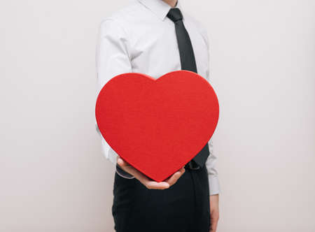 Man with big red heart gift in his hand on a white background. Love and Valentines day concept. copyspace.の写真素材