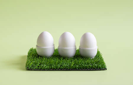 Easter eggs. Three chicken eggs in stands on a green background. Healthy organic food concept. copyspace.の写真素材