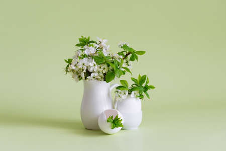 Easter minimal concept. Cherry blossoms spring bouquet and white egg on a green background. Flowers...
