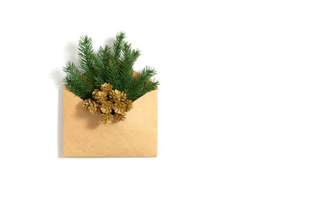 Spruce twigs and golden cones in a craft envelope isolated on a white background. Christmas greeting...