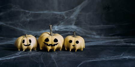 Halloween pumpkins in ghosts shape on a dark gray background with spiderwebs. Halloween greeting...