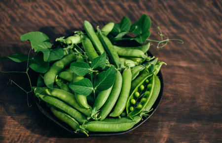 Green peas in a bowl on a wooden background close up. Green pea pods and leaves. Healthy food.の写真素材