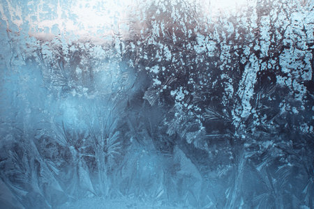 Blue winter background with frost pattern on the window. Beautiful frosty drawing. Frozen window glass.の写真素材