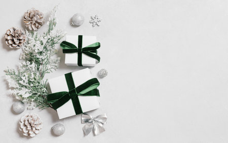 Christmas border with gifts, fir branch and cones on a gray background. Gifts with silver decor and green bows. Copy space. Top view, flat lay.の写真素材