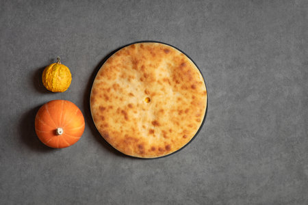 Ossetian pie with pumpkin. Pumpkin pie on a gray background with copy space. View from above.