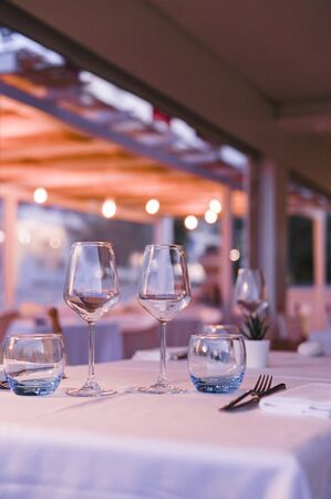 A glass of white wine on a table in a restaurant. Toned photo. Glare and light spots. Free space for textの写真素材