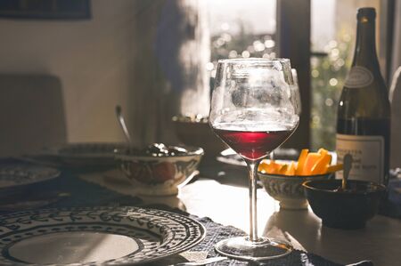 Glass of wine on the dining table. Sun glare. Toned photoの写真素材