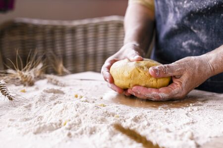 Women's hands, flour and dough. A woman in an apron is preparing dough for home baking. Rustic style...