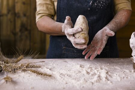Women's hands, flour and dough. A woman in an apron is preparing dough for home baking. Rustic...