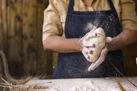 Women's hands, flour and dough. Levitation in the frame. A woman in an apron is preparing dough for...