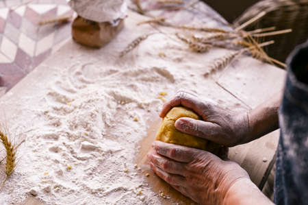 Female hands and dough. A woman is preparing a dough for home baking. Rustic style photo. Wooden table, wheat ears and flour. Free space for textの写真素材
