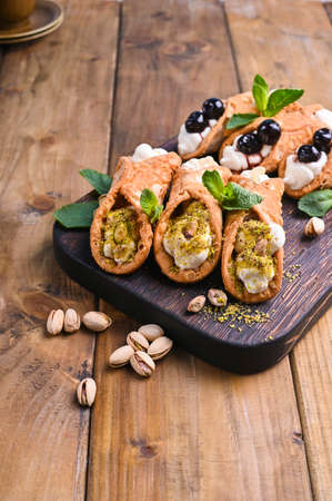 Cannoli Sicily. Traditional Italian sweet with ricotta and various fillings. Food on a wooden cutting board.の写真素材