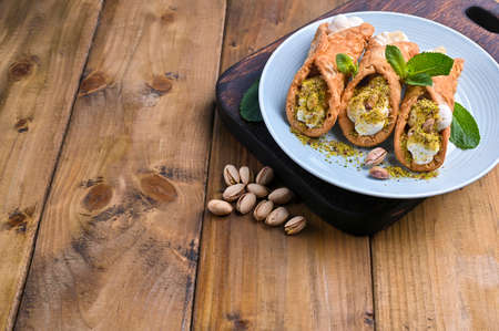Cannoli Sicily. Traditional Italian sweet with ricotta and various fillings. Food on a wooden cutting board. Delicious treats from the south of Italy. Copy space.の写真素材