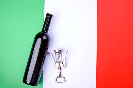 Wine bottle and corkscrew on the Italian flag. The concept of a winemaker and a traditional harvest festival in italy. Copy space. Flat layの写真素材