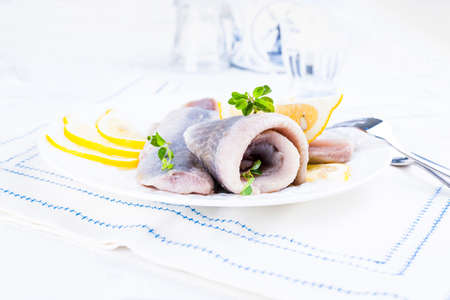 Dutch herring. Traditional Dutch food, marinated fish fillet with onion and lemon. Food high in nutrients and vitamins. Photo in light colors, free space for text.の写真素材