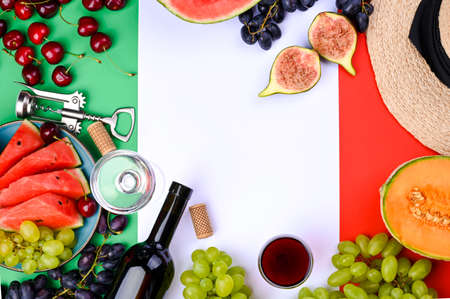 A bottle of wine, wineglass, grapes, different fruits and the flag of Italy. Country symbol backdrop. The concept of harvesting, august traditional summer vacation. Free space for text. Top viewの写真素材