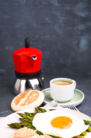 Healthy breakfast. Fried eggs, asparagus, bread and aromatic coffee on a gray background. Free place for text. Soft focus. High quality photoの写真素材