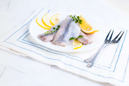 Dutch herring. Traditional Dutch food, marinated fish fillet with onion and lemon. Food high in nutrients and vitamins. Photo in light colors, free space for text.の写真素材