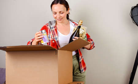 Unpacking the parcel. The woman opens the box and happily takes out the purchases from the online...