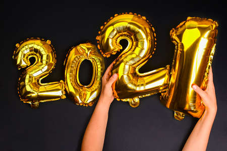 Happy New year 2021 celebration. Gold and silver foil balloons numeral 2021 on a black background. Postcards and posters. High quality photo. Copy spaceの写真素材