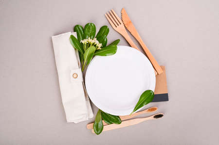 Paper plate, wooden toothbrushes, cotton bag, fresh green leaves on a gray background.Eco-friendly food packaging. Zero waste, eco friendly, plastic free background. recycling concept. Flat lay .の写真素材