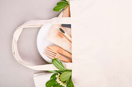 Eco craft paper tableware. A box of paper for food, cotton bag, Toothbrush, plate, forks, knives, on a gray background. world is free of plastic. Recycling concept eco-friendly . Close-Up. Copy space.の写真素材