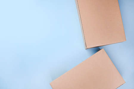 Craft unlabeled cardboard package box presented on stressed brushed on a blue background. The concept of delivery, mail, destinations, the quarantine period is relevant. Copy space. Aboveの写真素材