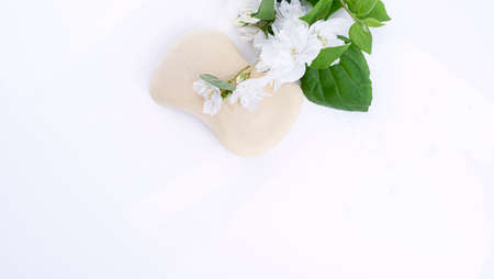 Soap with jasmine on a white background and fresh flowers. Beauty and care products in the spa. Free space for text. Copy spaceの写真素材