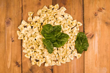 Dry butterfly pasta with spinach on a wooden background. Typical Italian cuisine. Top view. High...