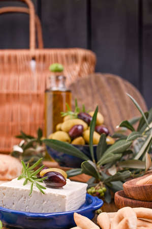 Greek cheese feta with thyme and olives, selective focus. Bread and young olives branch on olive board over old wood background. Overhead viewの写真素材