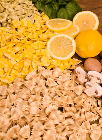 Dry Butterfly pasta with different flavors on a wooden background. Multi-colored pasta with spinach, mushrooms and lemon. Typical southern Italian cuisine. High quality photoの写真素材
