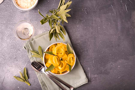 Italian pasta and white wine. Tortellini with sage, ricotta and spinach. Traditional Bologna cuisine, Emilia Romagna region. High quality photo. Copy space. Above. TOP VIEWの写真素材