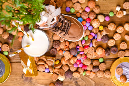 Dutch holiday Sinterklaas. Wooden background with childrens shoe with carrots for Santas horse, pepernoten and sweets . View from above. High quality photoの写真素材