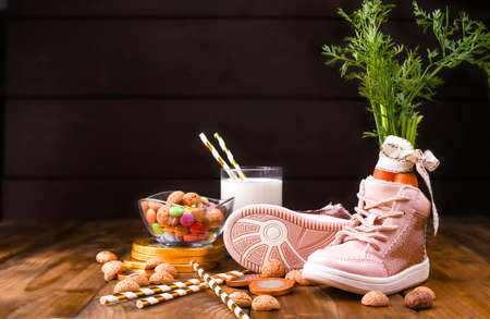 Wooden background with childrens shoe with carrots for Santas horse, pepernoten and sweets....