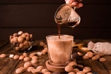 Espresso coffee poured into a glass of milk and Traditional sweets, cookies pepernoten on a wooden table. Copy space. Dutch holiday Sinterklaas. High quality photo.の写真素材
