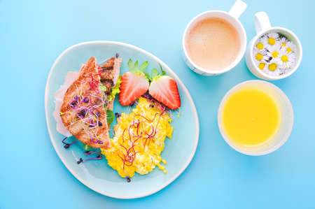 Coarse bread toast with ham, salad and scramble, sprinkled with sprouted seeds. Super food. Delicious healthy breakfast on a bright background. High quality photo. Top viewの写真素材