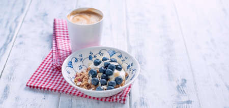 Granola with berries and fresh espresso on a white wooden background. Soft light in the frame. Free space for text.の写真素材