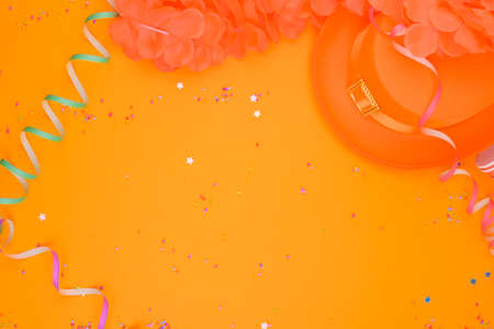 Decor for a traditional celebration of Kings Day in the Netherlands. Orange hat, glasses, jewelry and confetti on a bright background. Picture in the form of a frame. Copy space. Horizontal format.の写真素材