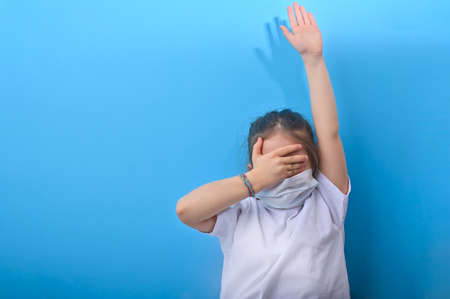 ittle girl in a protective medical mask closes her eyes with her hands. The emotions of the child in the photo. Copy spaceの写真素材