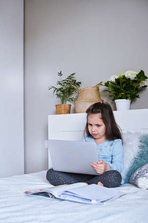 Distance learning online education. Schoolgirl with digital tablet laptop notebook and doing school...