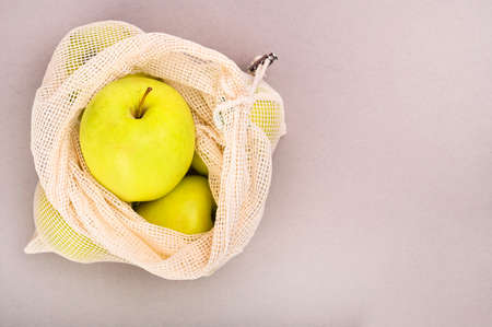 An Overhead View Of Fruits In Net Bag Over on a gray background. Zero waste concept. White wall...