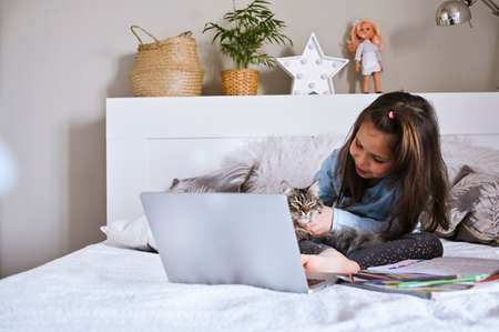Distance learning online education. Schoolgirl with digital tablet laptop notebook and doing school...