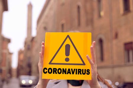 Coronavirus. Text on a sign symbolizing danger. Pandemic 2019 and 2020. Girl in the city of Italy.の写真素材