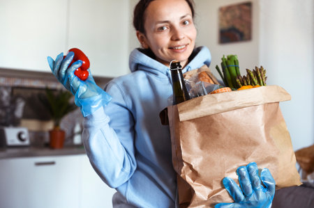 A person smiling for the camera with a set of food in hand.. Paper bag with Food supplies crisis food stock for quarantine isolation period. Food delivery, Donation, coronavirus. Soft focus.の写真素材