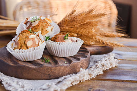Delicious homemade coconut cinnamon muffins and caraway leafs on old white tray. Healthy food concept with copy space. Against the background of dry ears of wheat. in the style of rusticの写真素材