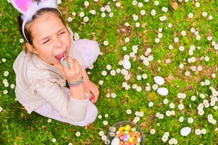 Easter eggs in the grass. A child collects traditional colored eggs and sweets in the garden. The concept of entertainment with children.Happy child. Copy space . Close-upの写真素材