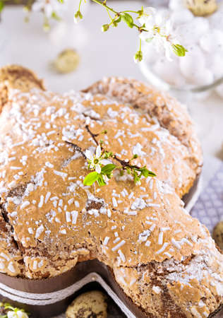 Traditional Italian desserts for Easter - Easter dove. Festive pastries with almonds and sugar icing on a light background and flowering branches, Easter decor and eggs. vertical. close-upの写真素材
