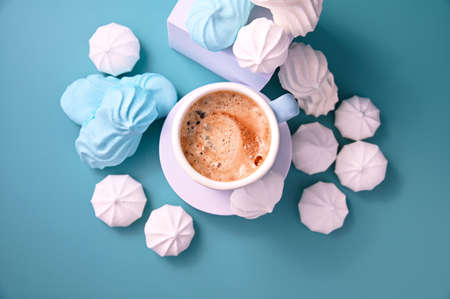 Meringue. Espresso with froth and meringues of different colors on a blue background. A creative shot of protein and sugar cookies. View from above. High quality photo. Copy spaceの写真素材