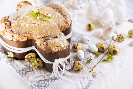 Traditional Italian desserts for Easter - Easter dove. Festive pastries with almonds and sugar icing on a light background and flowering branches, Easter decor and eggs. close-upの写真素材